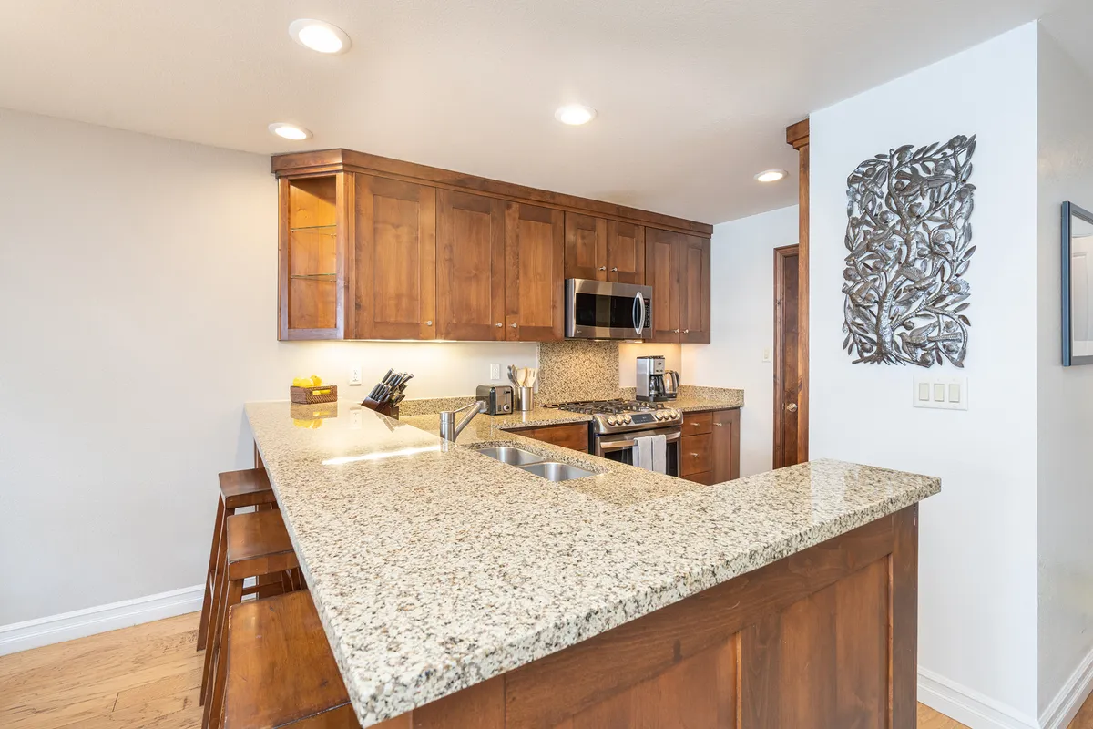 A stylish kitchen view highlighting a granite countertop, wood cabinets, and up-to-date appliances. The scene radiates warmth and invites guests to imagine themselves preparing meals or socializing in the space.