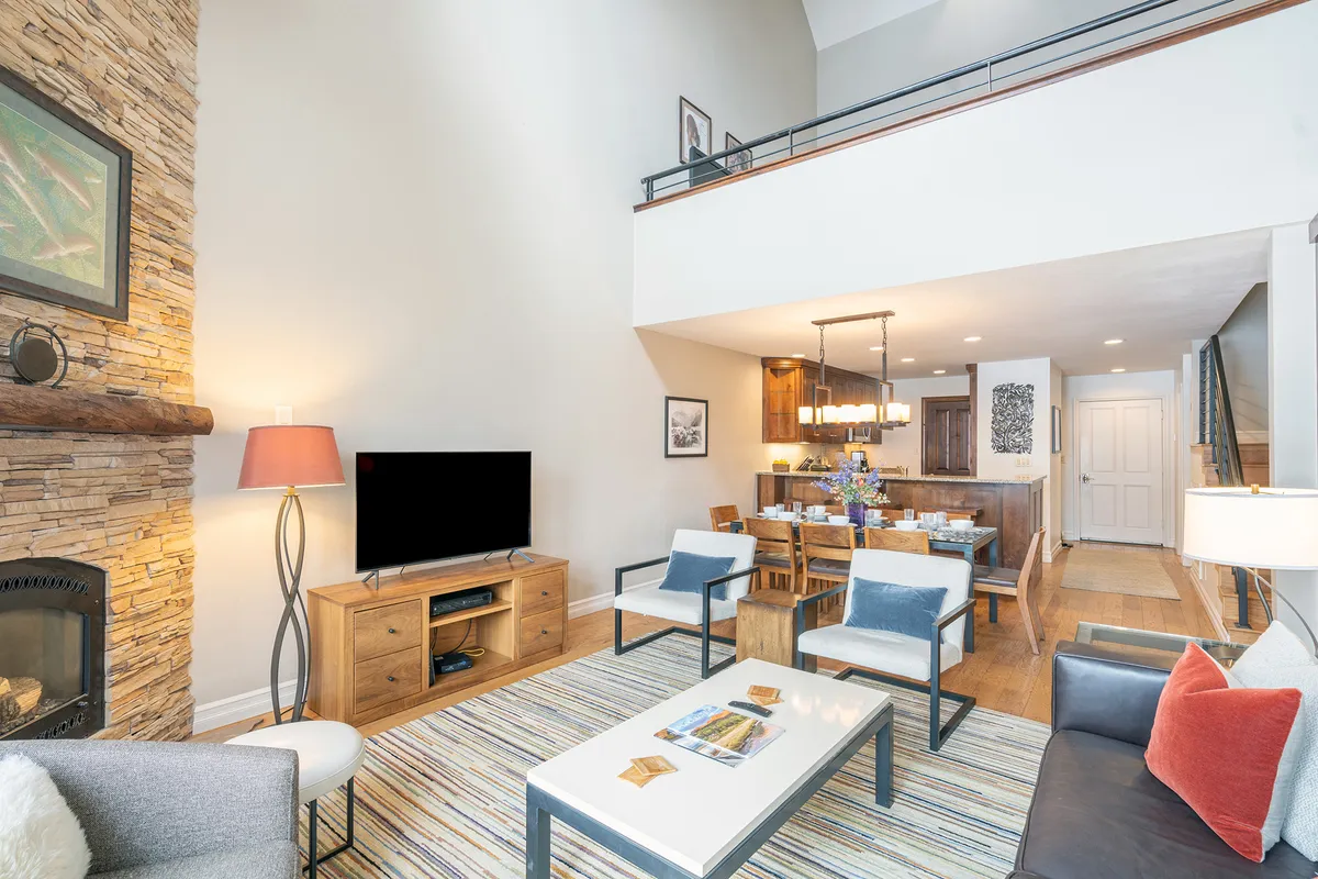 An open-plan living and dining area with a cozy fireplace, a six-person dining table, and a comfortable sofa arrangement. The dining nook is positioned to encourage conversation, while the fireplace adds ambiance and visual connection to shared spaces.