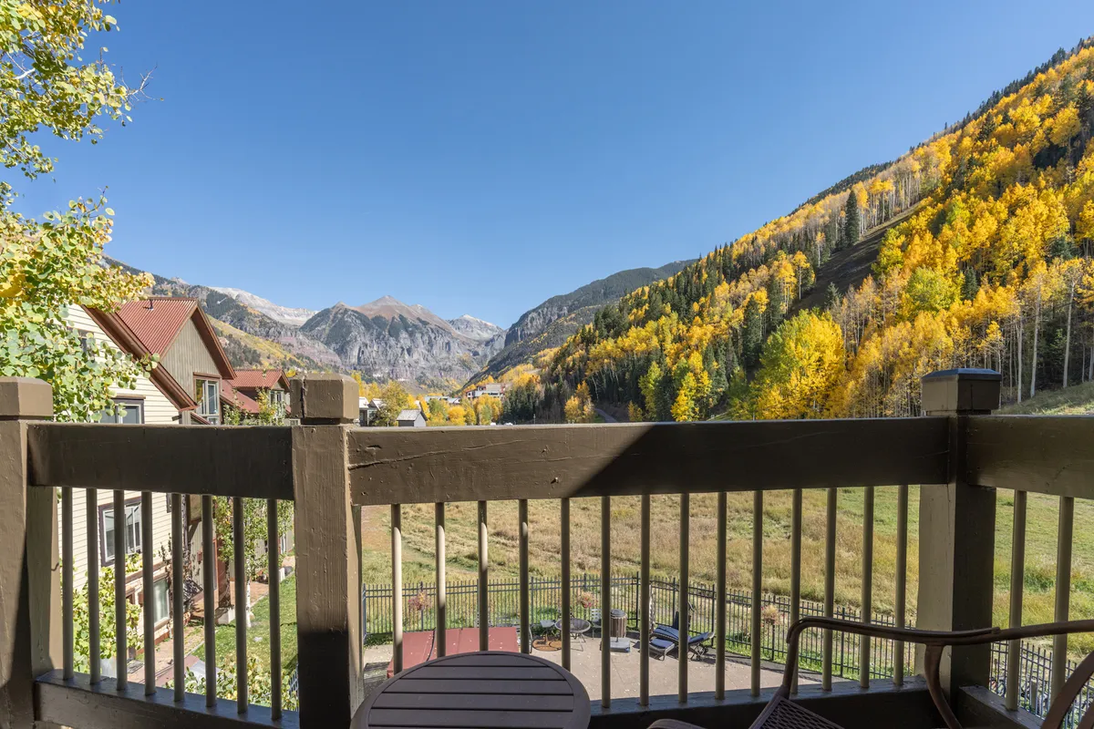 A serene private deck with comfortable outdoor furniture overlooks a breathtaking mountain range adorned in fall foliage. The inviting setting captures the peace and beauty of Telluride's natural surroundings, offering a seamless transition from indoor relaxation to outdoor exploration.